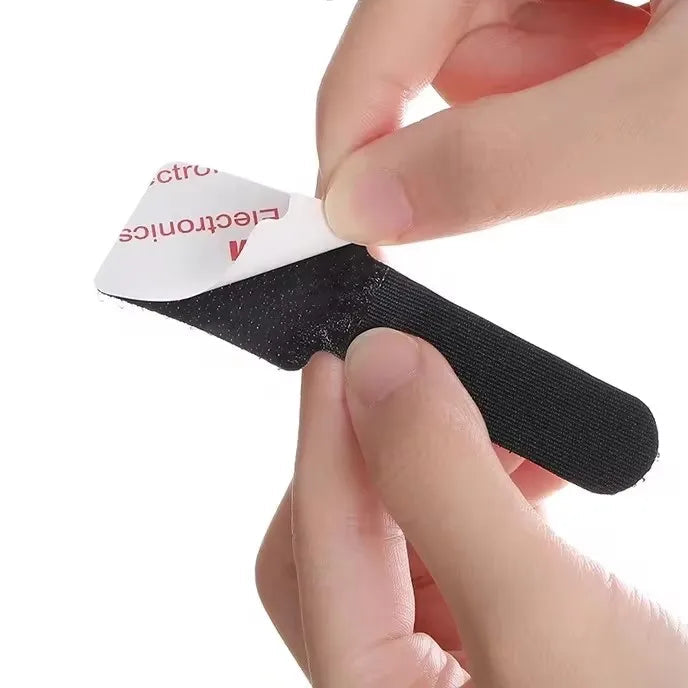 Black adhesive strip with a hand applying it, cable organizer.